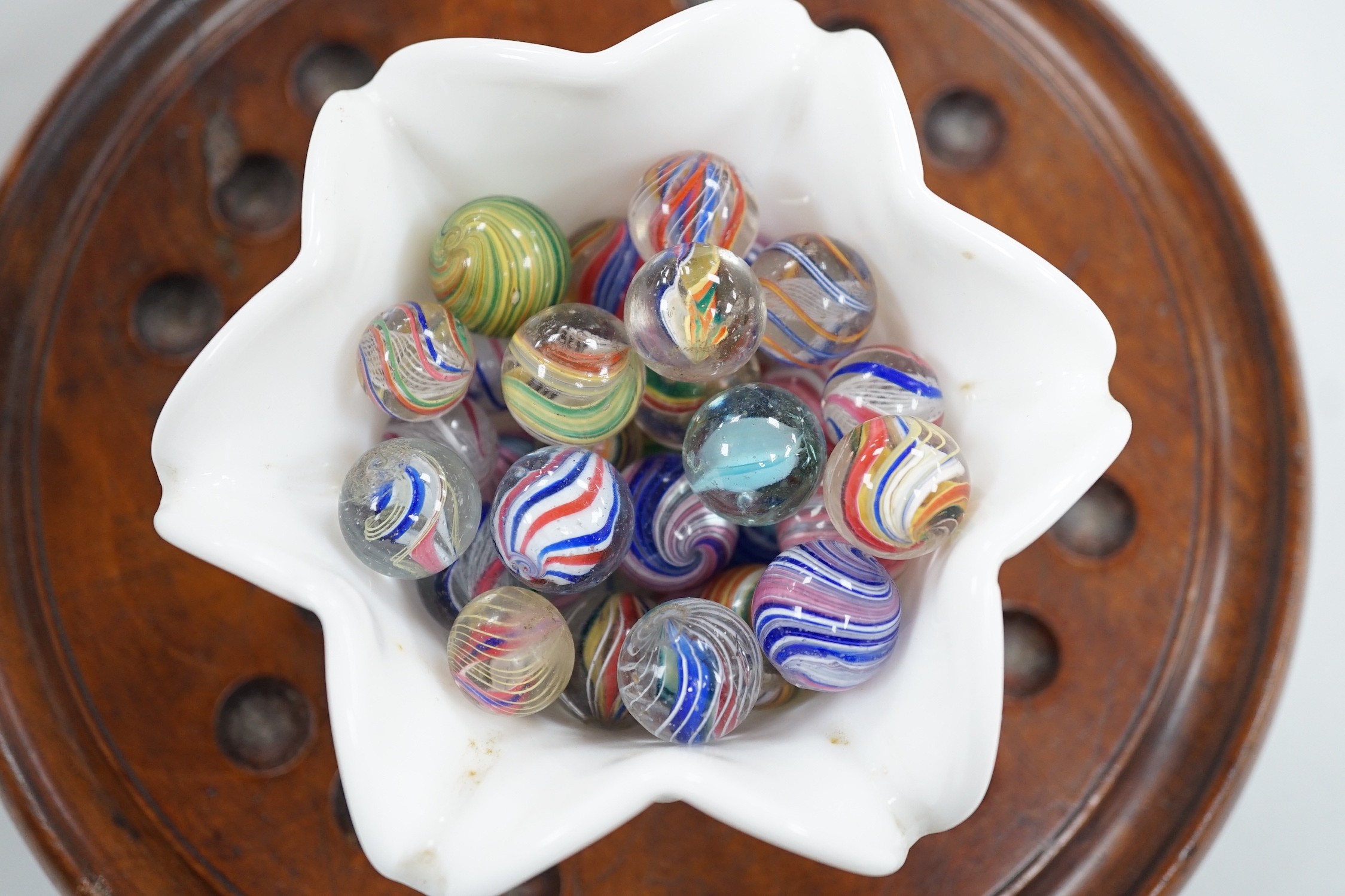 A mahogany solitaire board with a collection of latticino and marbled glass marbles